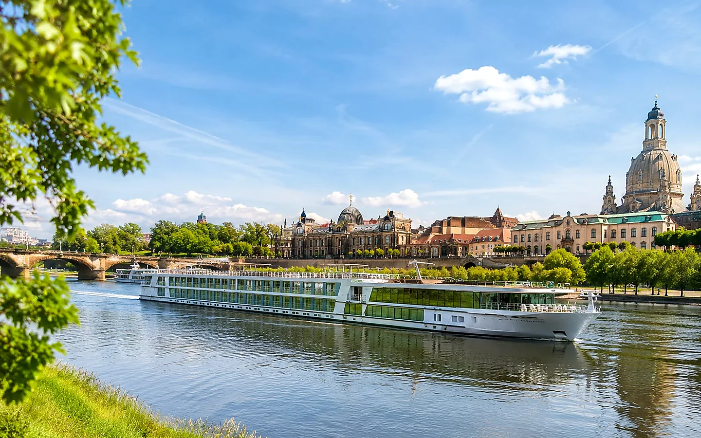 Helle Elblandschaft mit Flussschiff, historischer Stadtsilhouette und grünen Ufern