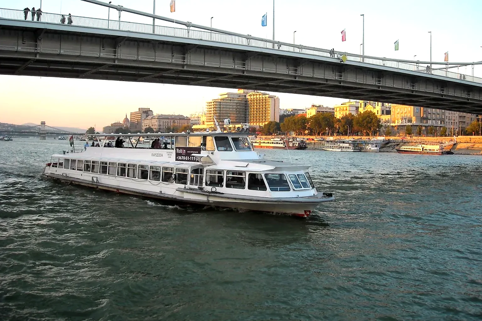 Helles Flusspanorama mit Schiff und historischer Stadt an einem weitläufigen Wasserweg
