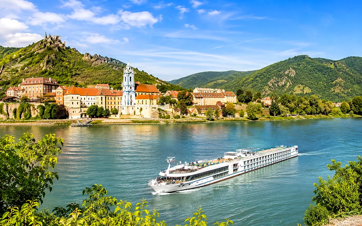 Sonnige Donau-Flussreise mit modernem Flussschiff zwischen grünen Ufern